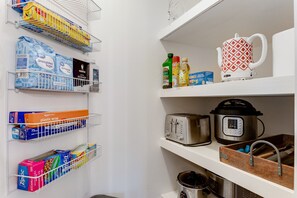A kitchen with shelves holding various food items, a kettle, a toaster, and a slow cooker. - Hot Tub Hideaway - Firepit - Big Families (Loveland)