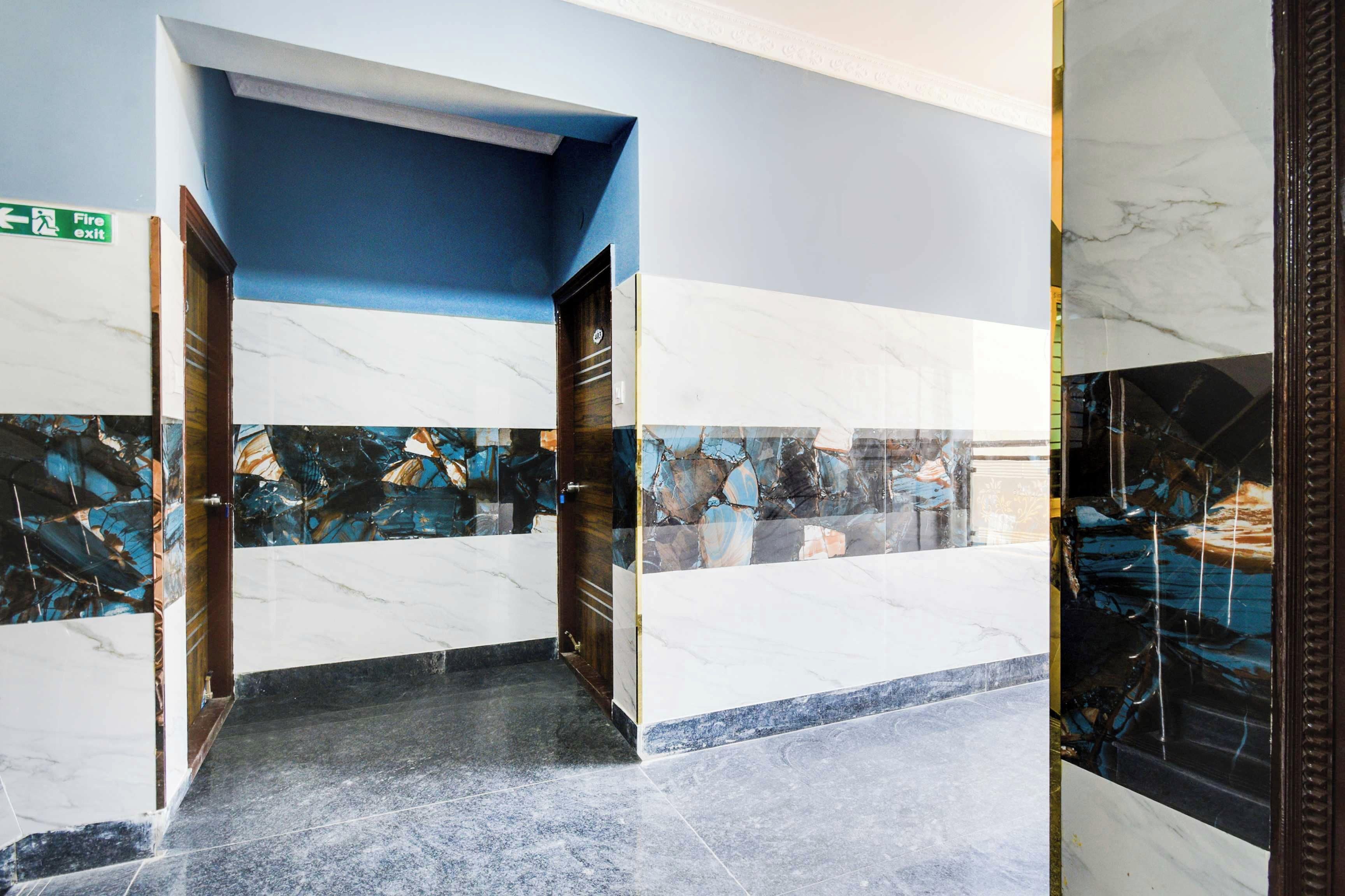 Un pasillo con piso de mármol, una pared azul decorativa y una puerta con placa de identificación.