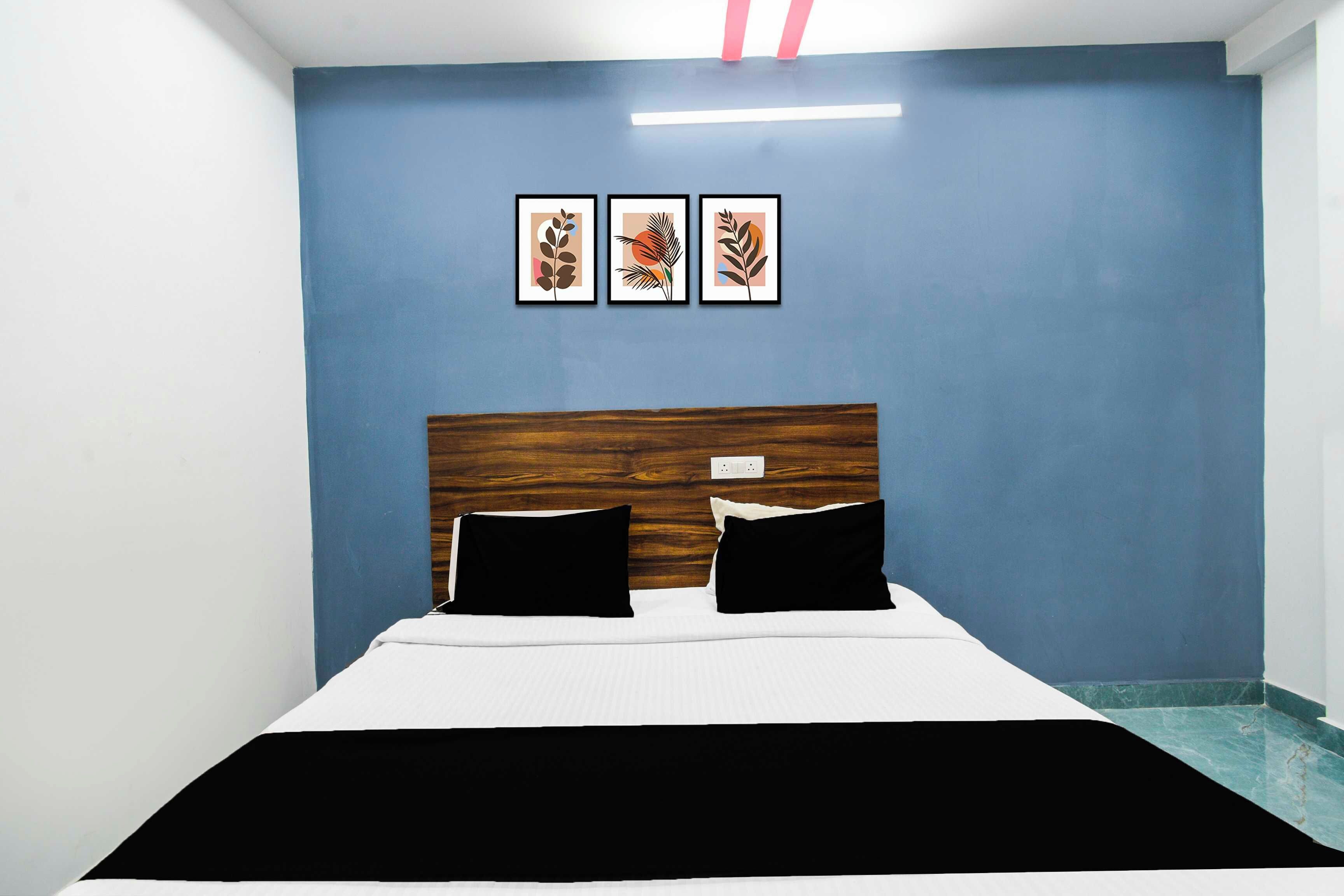 A room with a bed, a blue wall, and three framed pictures.