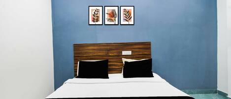 A room with a bed, a blue wall, and three framed pictures.