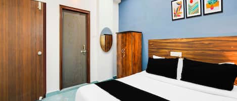 A hotel room with a bed, a wardrobe, a door, and wall-mounted artwork.