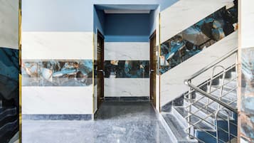 Una escalera de mármol con barandillas de metal que lleva a una puerta.