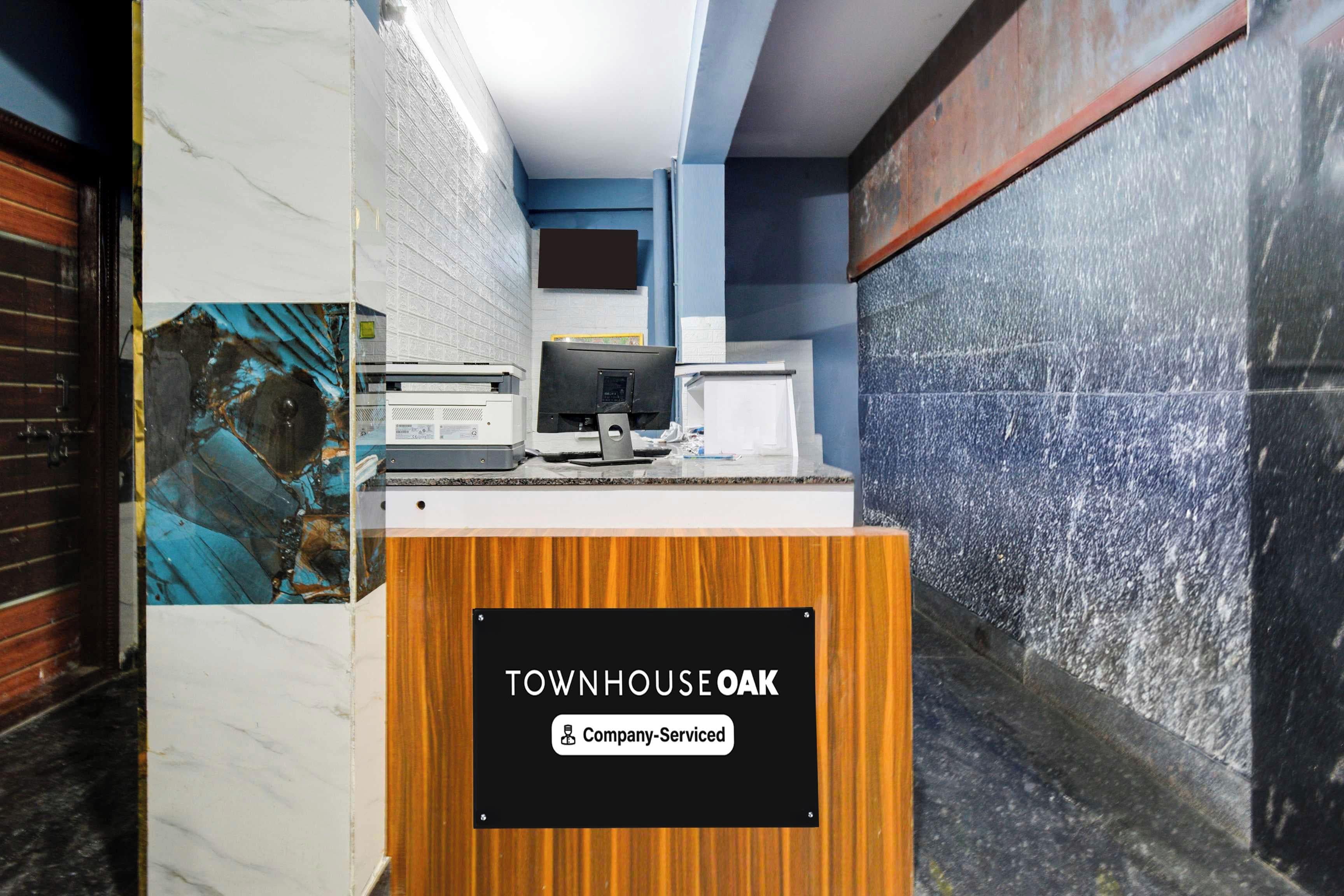 Una recepción con un cartel que dice 'TOWNHOUSE OAK' y un rótulo que indica 'Servicio de empresa'.