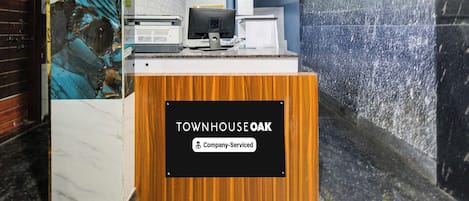 En receptionsdisk med et skilt, der viser 'TOWNHOUSE OAK', og en mærkat med teksten 'Virksomhedsbetjent'.