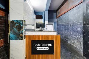 A reception desk with a sign reading 'TOWNHOUSE OAK' and a 'Company-Serviced' label. - Townhouse Oak Ardha Nareeshwar Temple (Hyderabad)