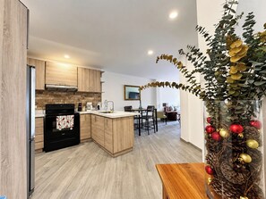 A modern kitchen with wooden cabinets, a black oven, and a dining area with a table and chairs.