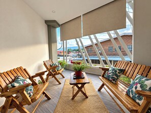A balcony with wooden furniture, a table, and potted plants.