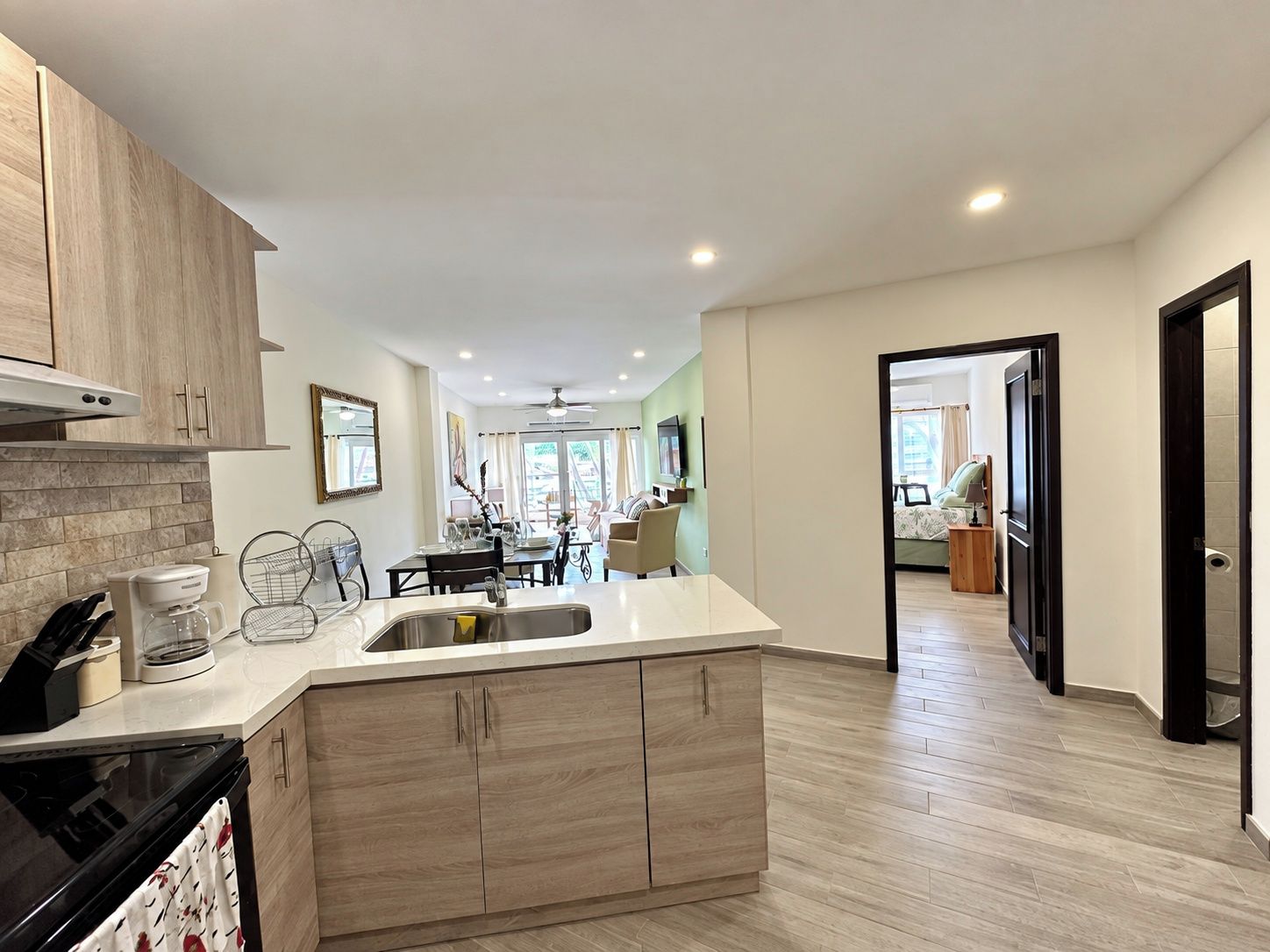 A modern kitchen with a central island, wooden cabinets, and a dining area in the background.