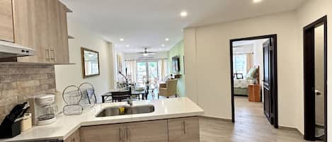 A modern kitchen with a central island, wooden cabinets, and a dining area in the background.