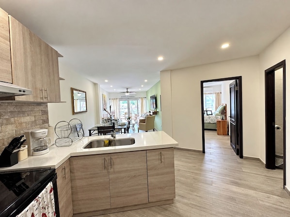 A modern kitchen with a central island, wooden cabinets, and a dining area in the background.