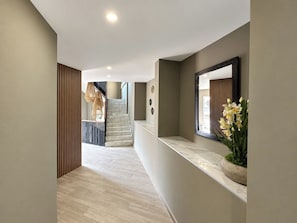 A modern interior with a marble staircase, a wooden slatted wall, and a marble counter with a potted plant.