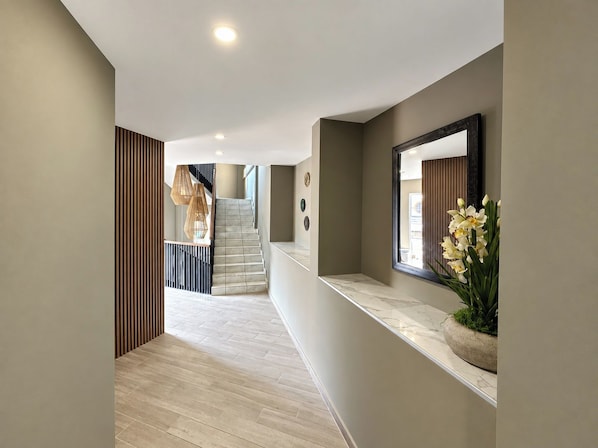 A modern interior with a marble staircase, a wooden slatted wall, and a marble counter with a potted plant.