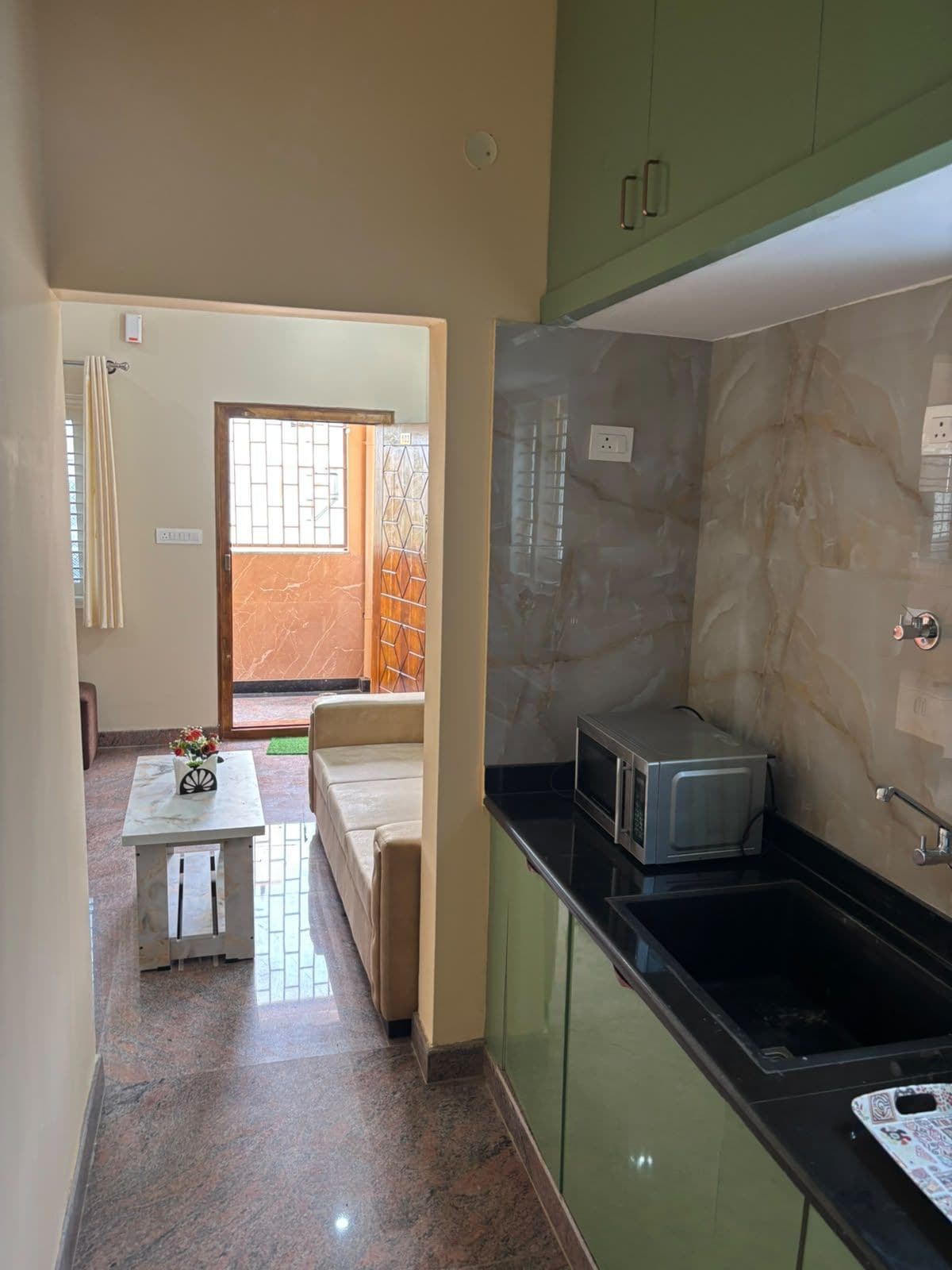Una cocina con microondas, un lavamanos y una zona de comedor con mesa y sillas.