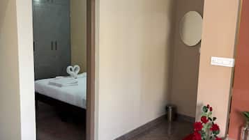 Una habitación de hotel con una cama, una mesa con un florero, un espejo y un armario.