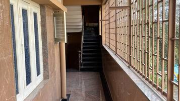 A corridor with a marble floor, a staircase, and a window with metal bars.