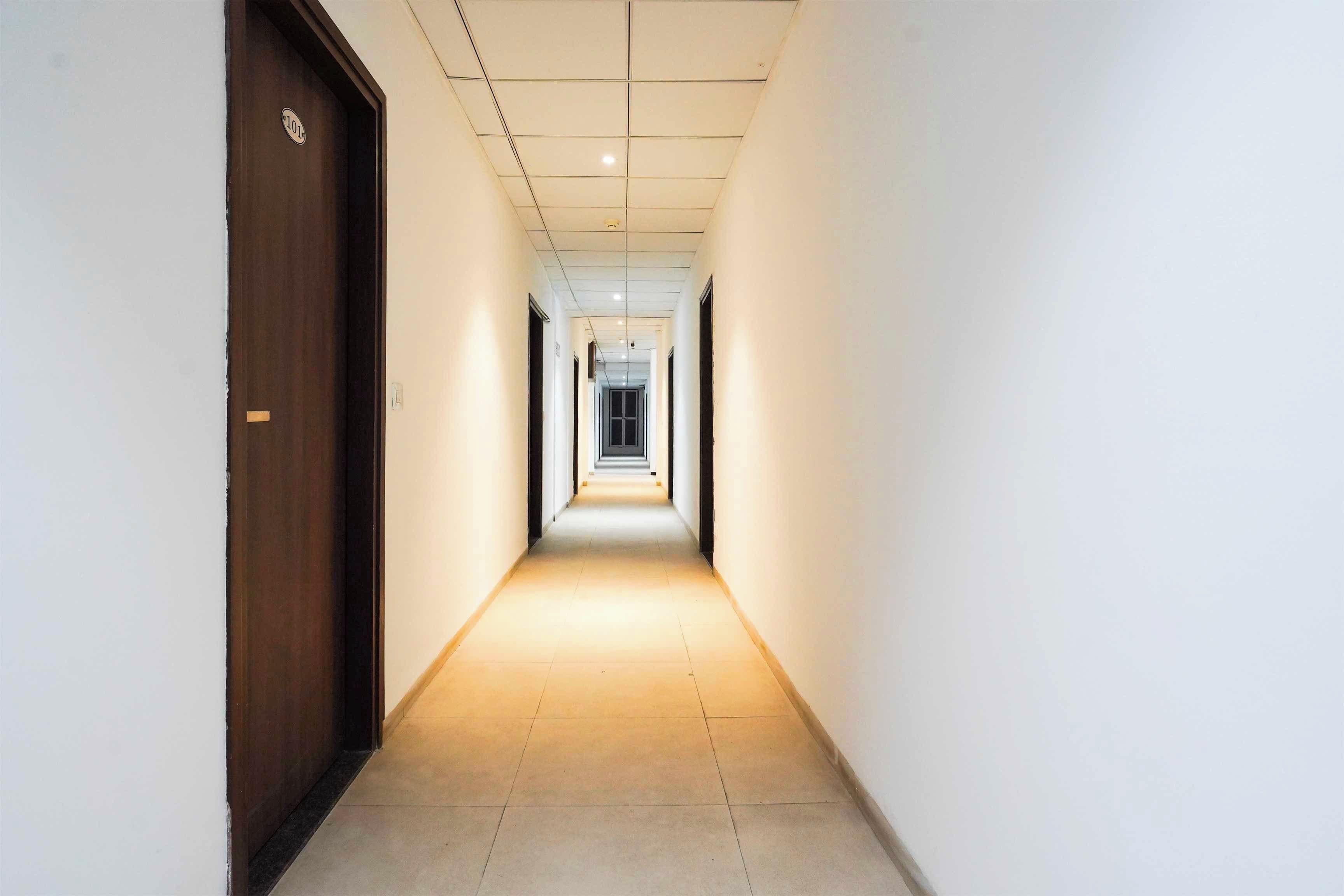 Corredor com porta de madeira à esquerda e chão de azulejos.