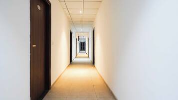 Corredor com porta de madeira à esquerda e chão de azulejos.