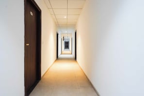 A corridor with a wooden door on the left and a tiled floor.