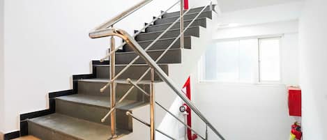 Una escalera con barandillas de metal y un extintor en la pared.