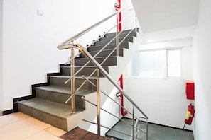 Un escalier avec des rampes en métal et un extincteur fixé au mur.