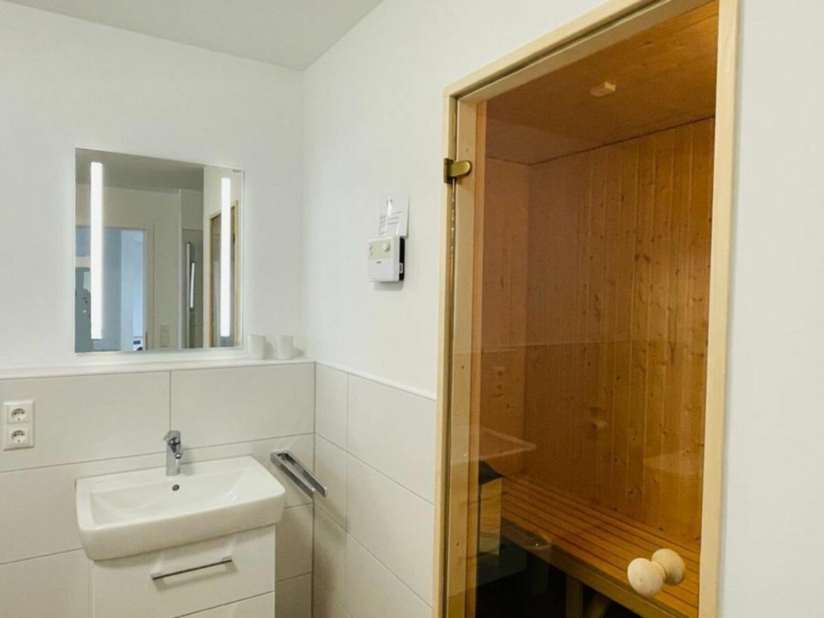 Ein Badezimmer mit einem weißen Waschbecken, einem Spiegel und einer Holztür.