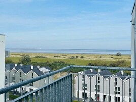 A residential area with modern houses, a view of the sea, and a clear sky.