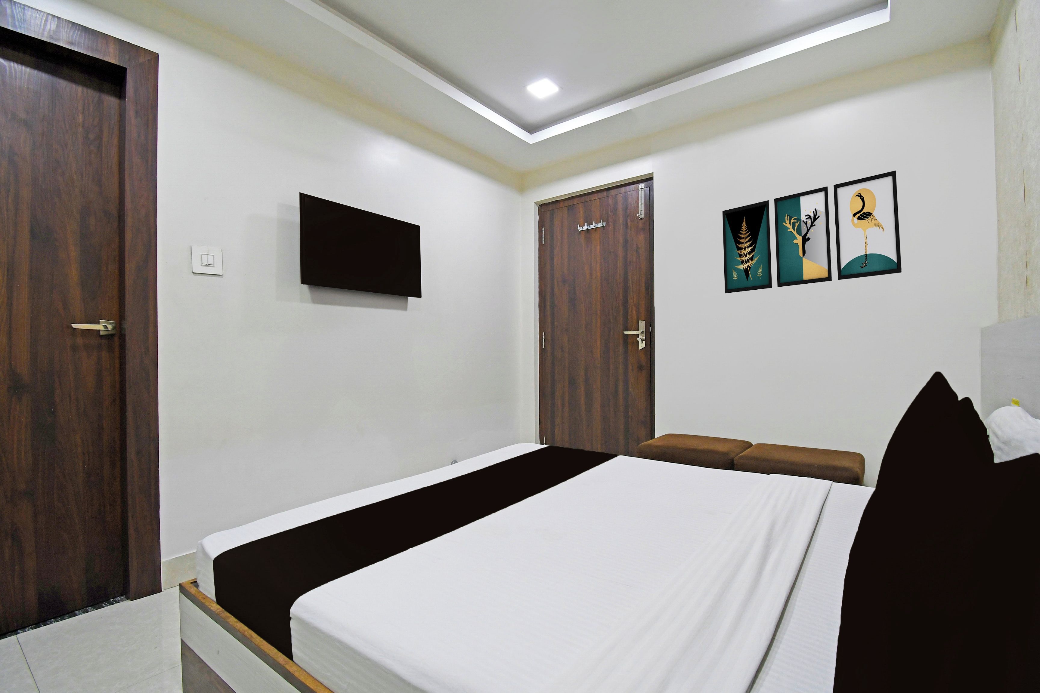 Quarto com cama, guarda-roupa, televisão e obras de arte na parede.