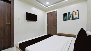 Quarto com cama, guarda-roupa, televisão e obras de arte na parede.