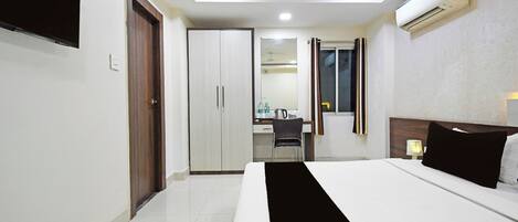 A hotel room with a bed, a desk, a chair, and a wardrobe.