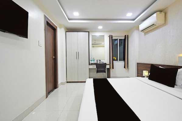 A hotel room with a bed, a desk, a chair, and a wardrobe.
