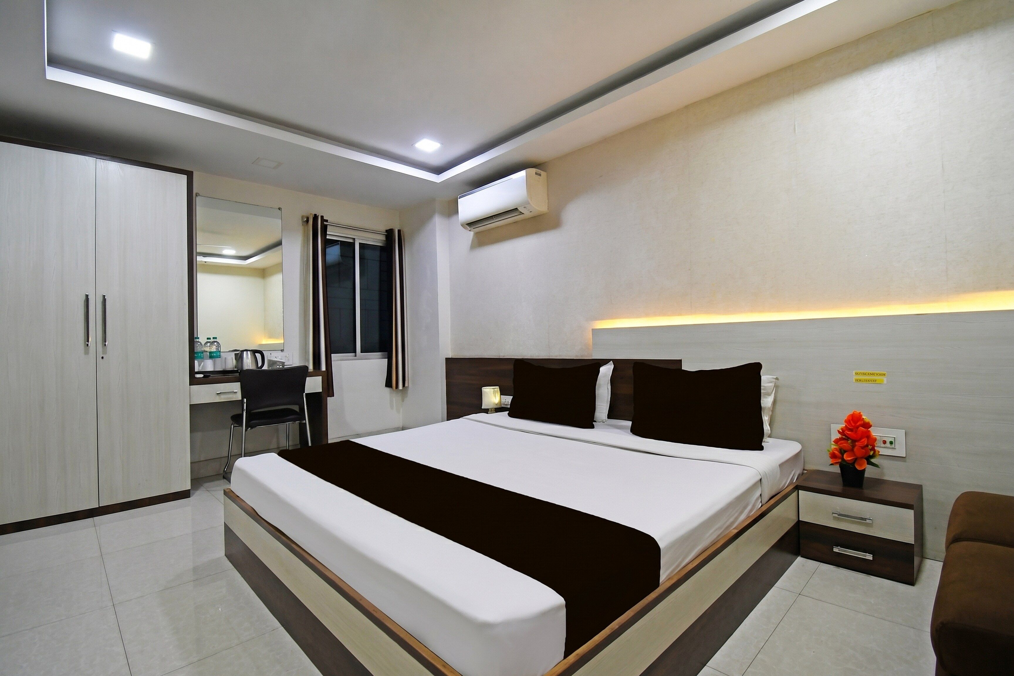 Una habitación de hotel moderna con una cama grande, un escritorio con una silla, un armario y un equipo de aire acondicionado.