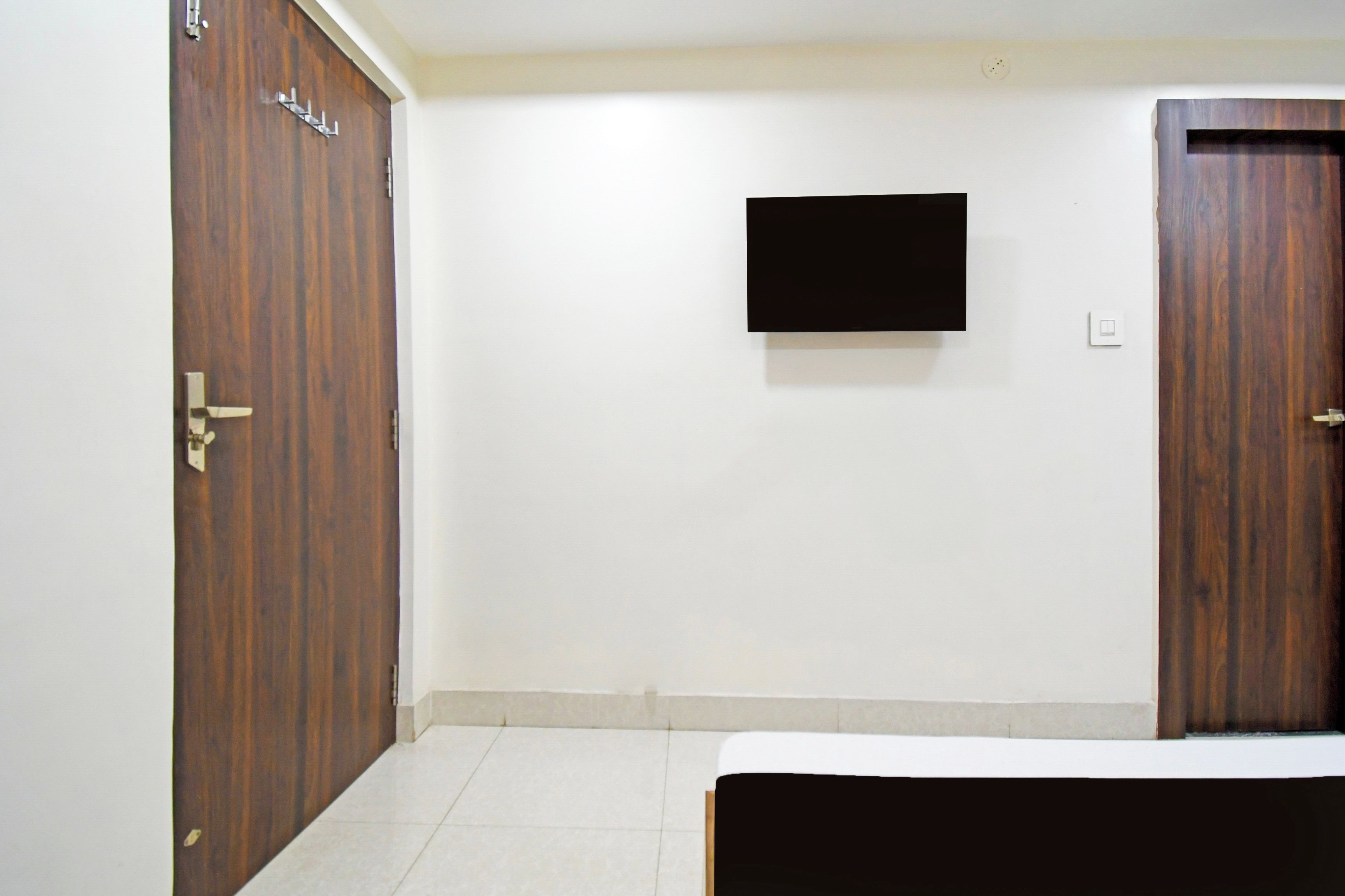 A room with a bed, a wardrobe, and a flat-screen TV mounted on the wall.