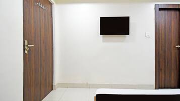 A room with a bed, a wardrobe, and a flat-screen TV mounted on the wall.