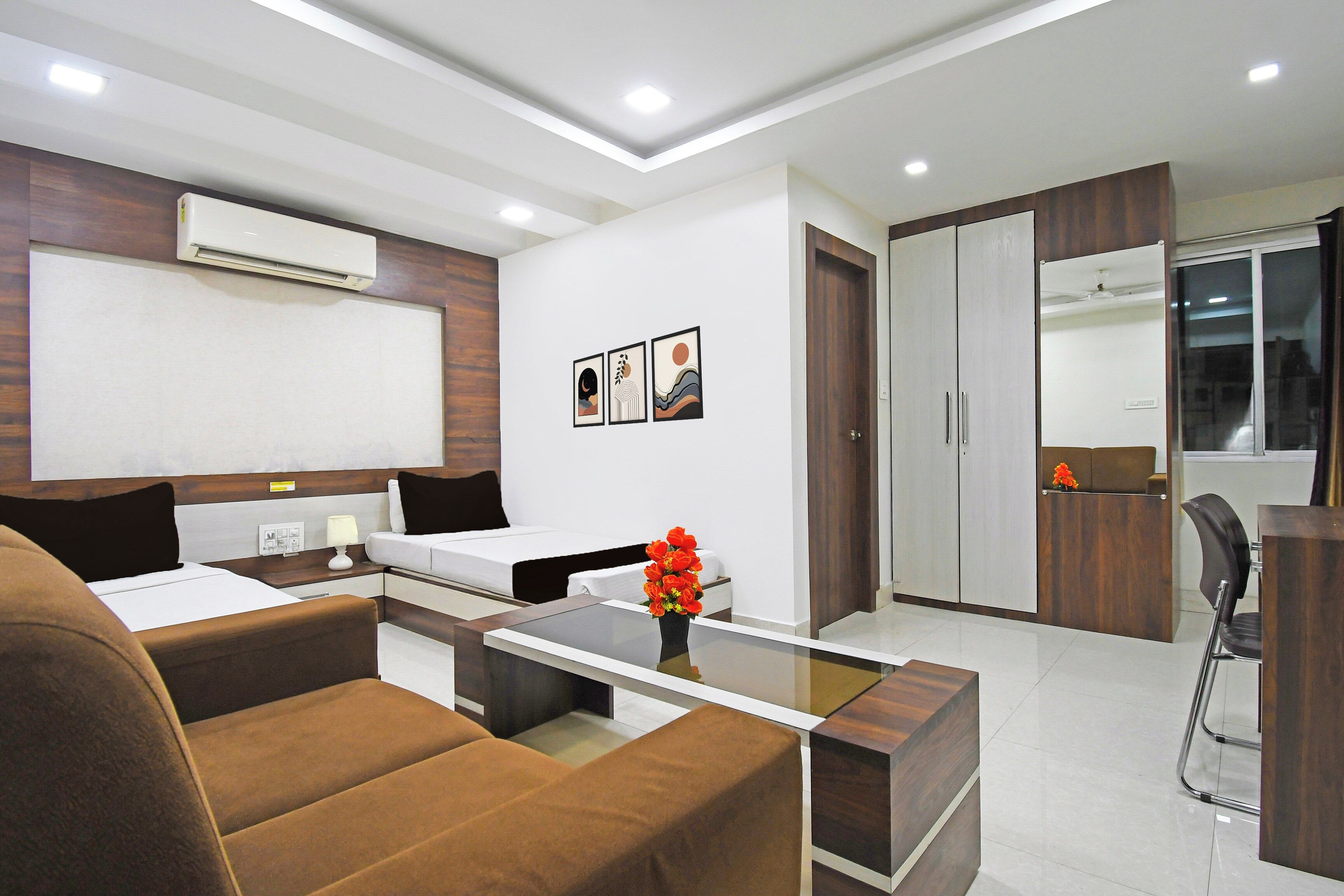 Una habitación de hotel moderna con cama, escritorio, silla, sofá y baño con espejo y armario.