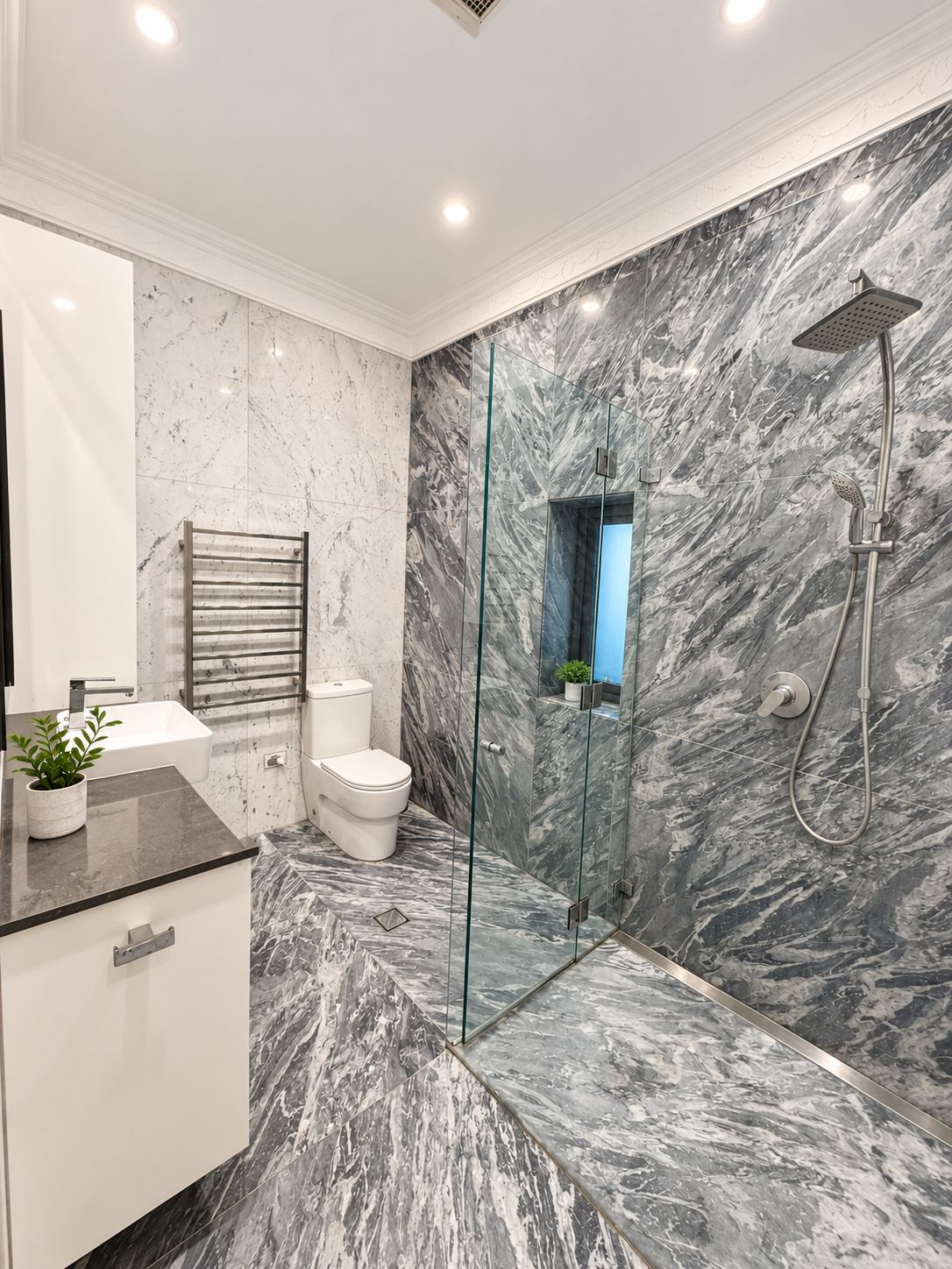 A modern bathroom with a glass-enclosed shower, a white toilet, and a marble-tiled floor.