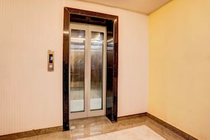 Un ascensor amb pantalla digital, panell de control i porta de vidre.