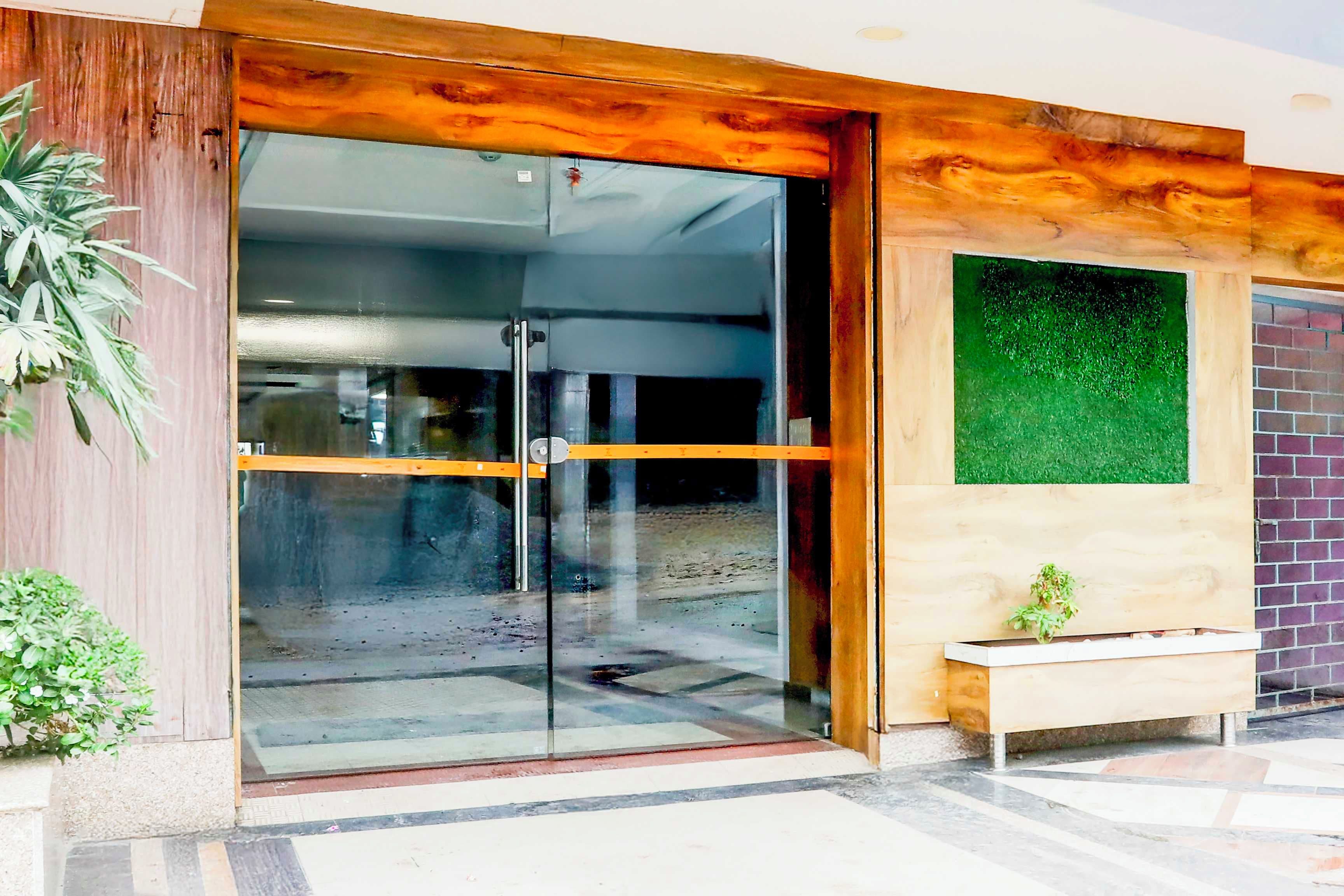 A modern building entrance with a glass door, a wooden frame, and a bench outside.