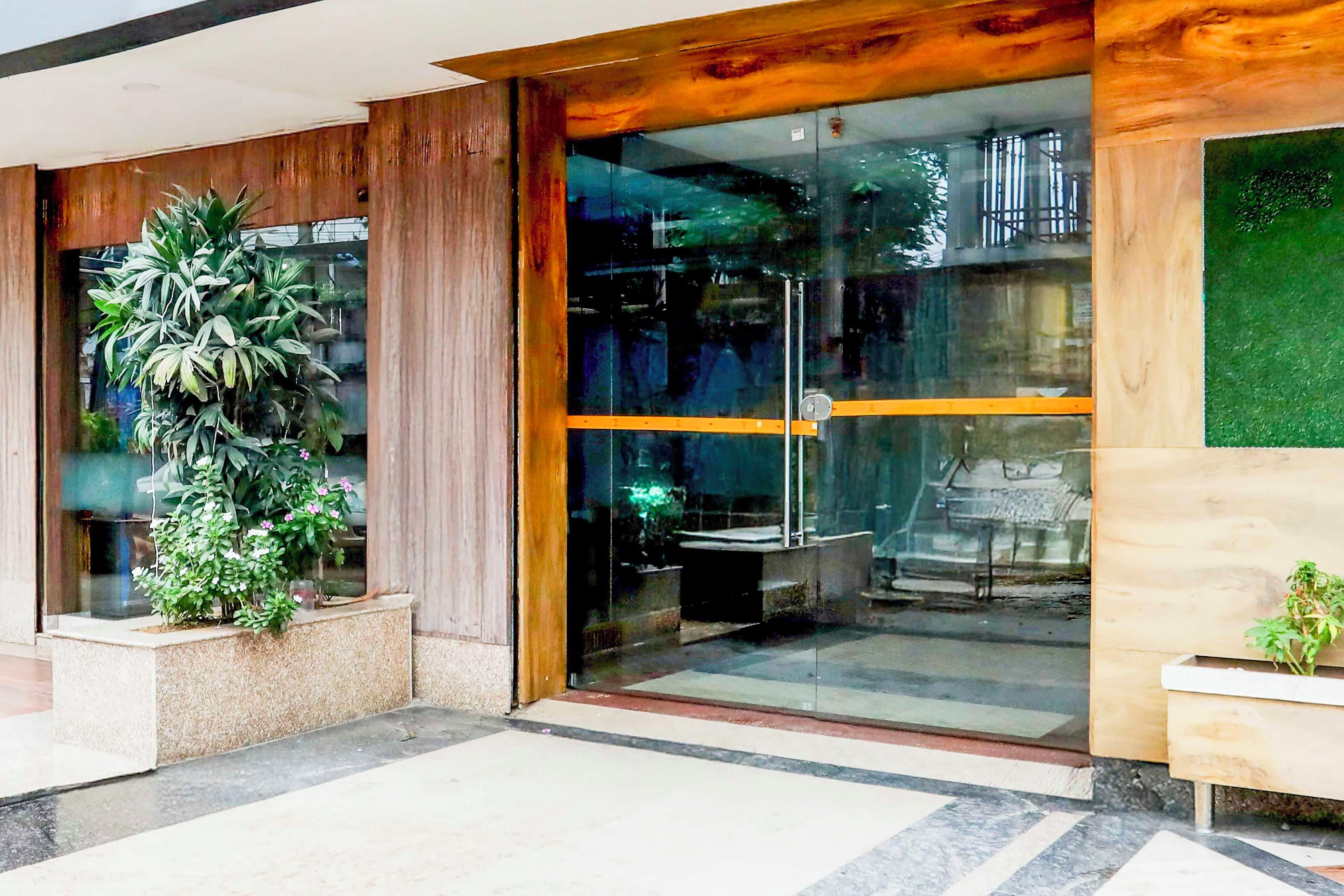 A hotel entrance with a glass door, a potted plant, and a wooden wall.