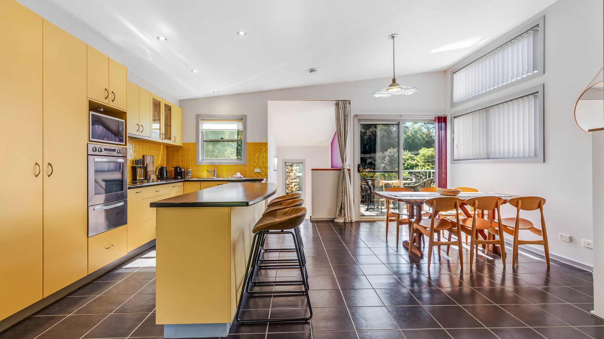 A modern kitchen with a central island, built-in appliances, and a dining area with a view of the outdoors.