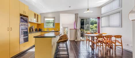 Una cocina moderna con una isla central, electrodomésticos integrados y un comedor con vistas al exterior.