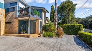 Ein modernes, zweistöckiges Haus mit Balkon, befestigter Auffahrt und gepflegtem Garten.