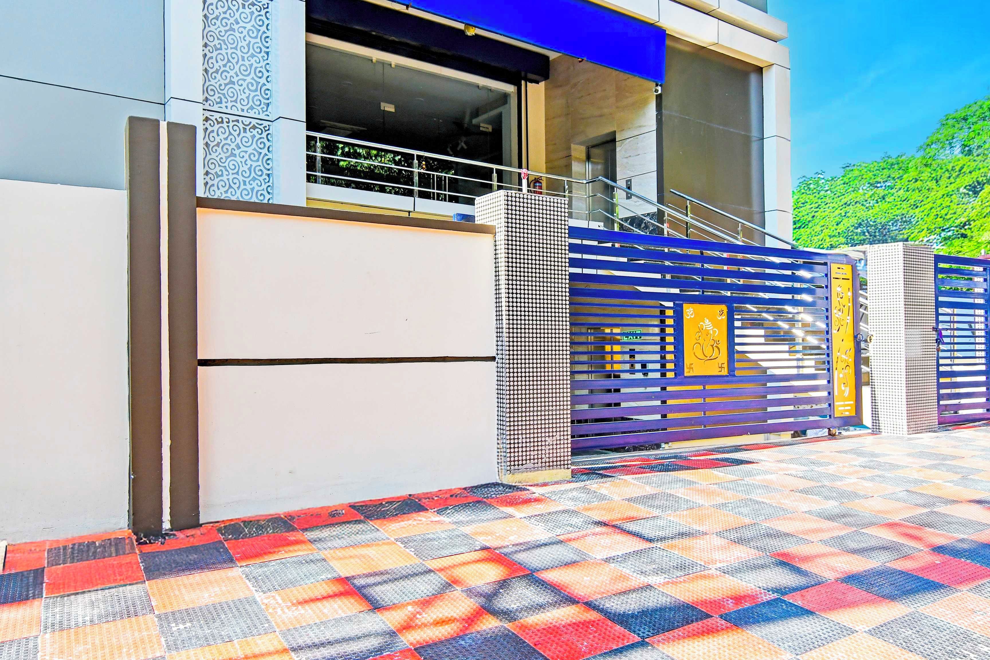 Entrada de un edificio moderno con piso estampado y un portón azul y amarillo.