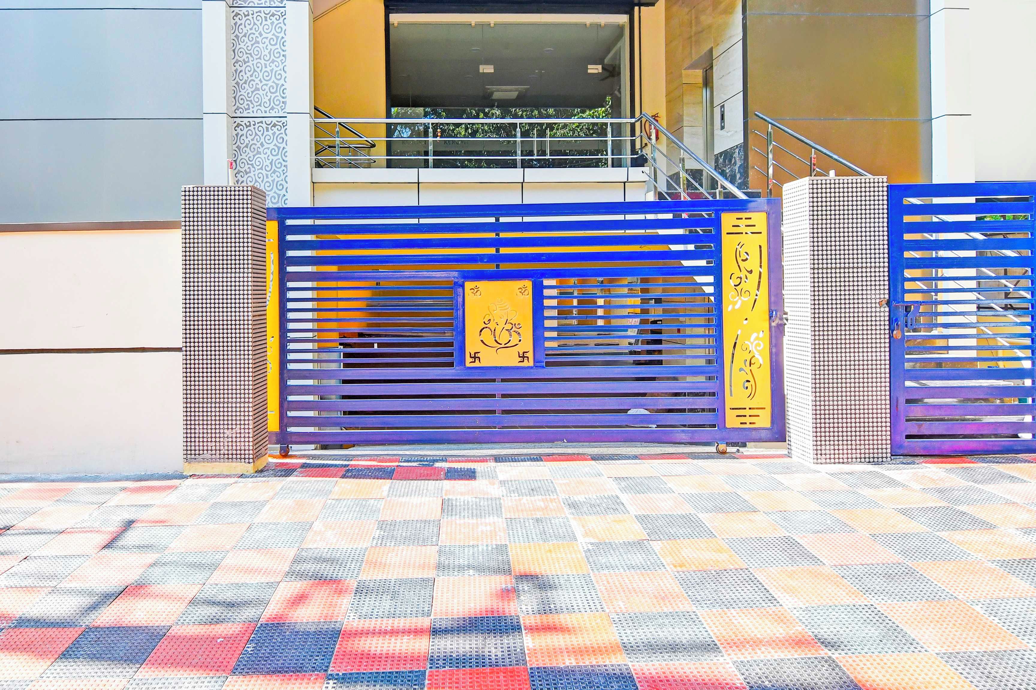 Entrada de um edifício com portão azul e amarelo, rampa e piso estampado.