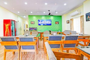 A conference room with wooden tables and chairs, a green accent wall, and a large screen.