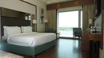 A hotel room with a large bed, a desk, a chair, and a balcony.