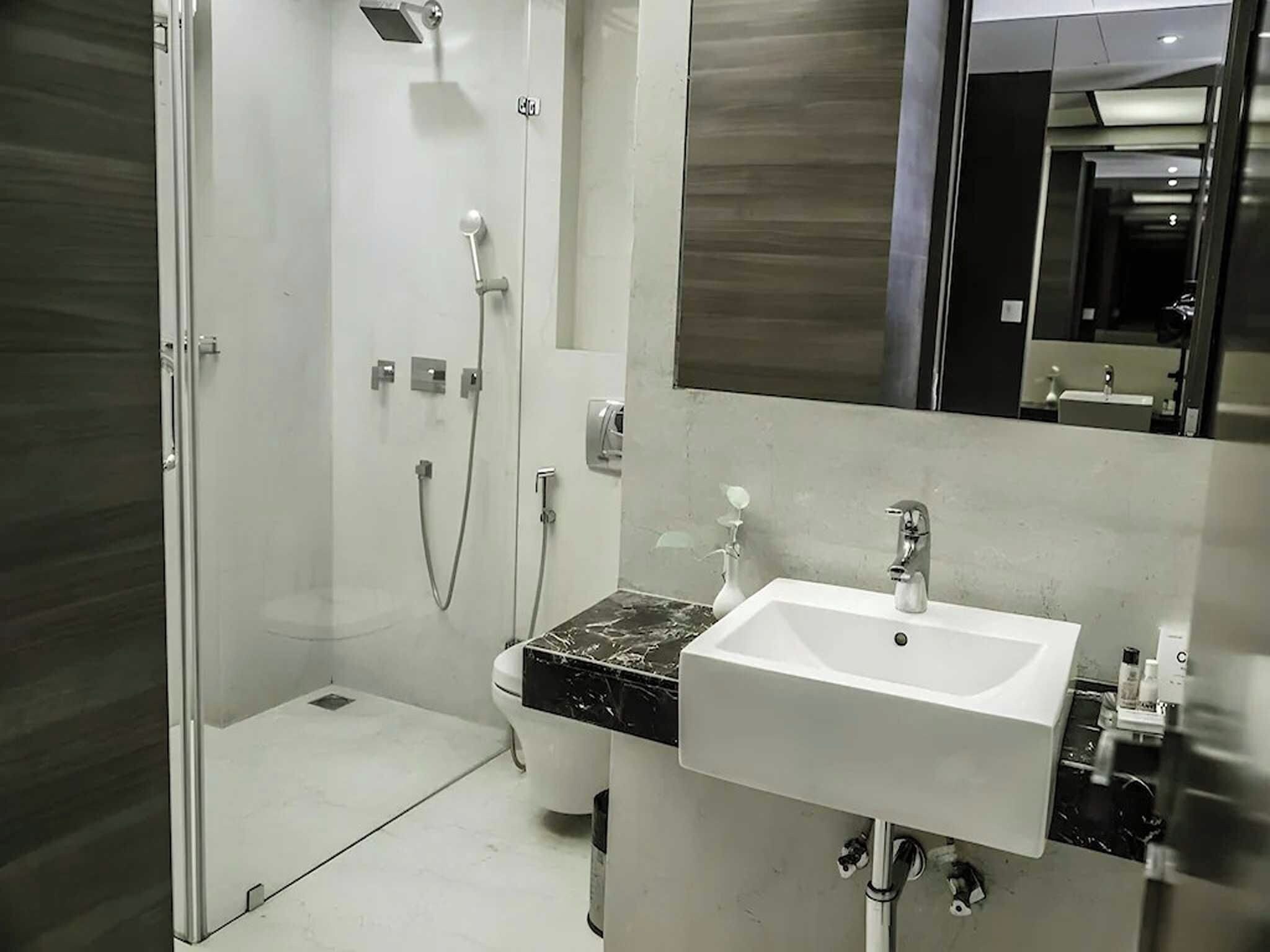 Un baño moderno con cabina de ducha de vidrio, un lavabo blanco y un espejo grande.