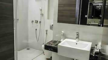 Un baño moderno con cabina de ducha de vidrio, un lavabo blanco y un espejo grande.