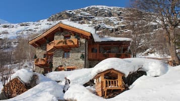 Een chalet met een stenen gevel, houten balkons en een met sneeuw bedekte dak.