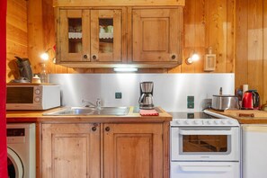 Una cocina con armarios de madera, un lavamanos de acero inoxidable, una cafetera, un tostador y un microondas.