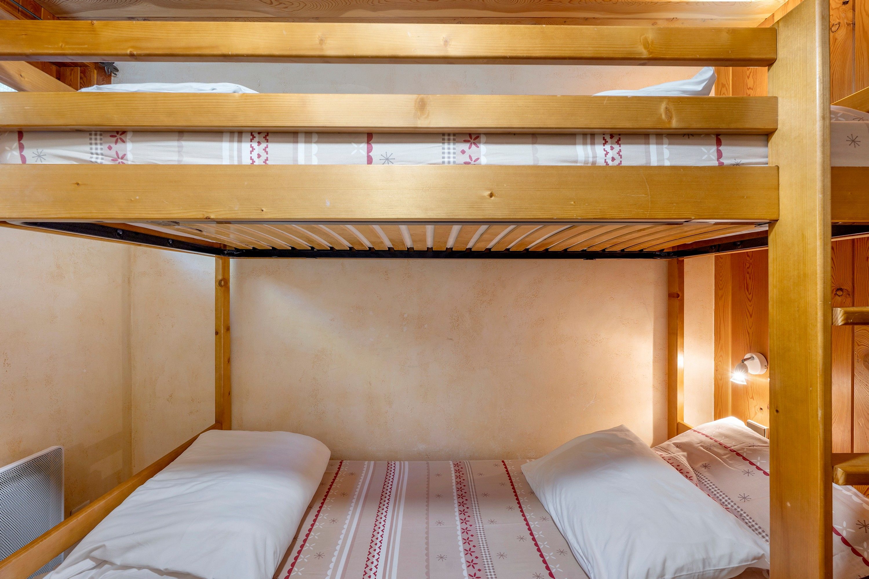 Een stapelbed met houten frame, inclusief een onderbed met matras en kussens.